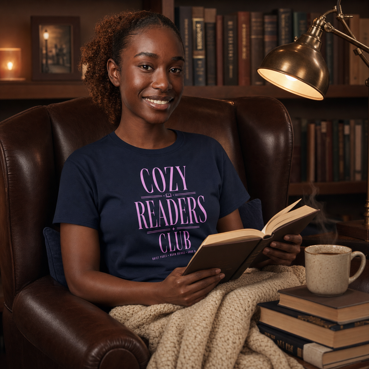Woman reading in a cozy library while wearing the Navy Cozy Readers Club tee
